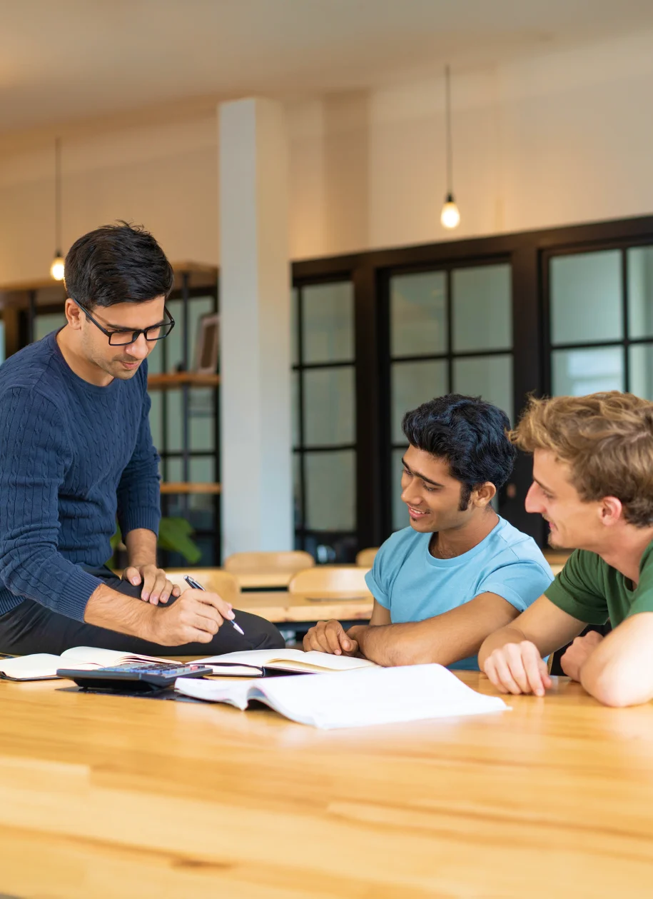 Three young men studying together at a table at Prestige University.